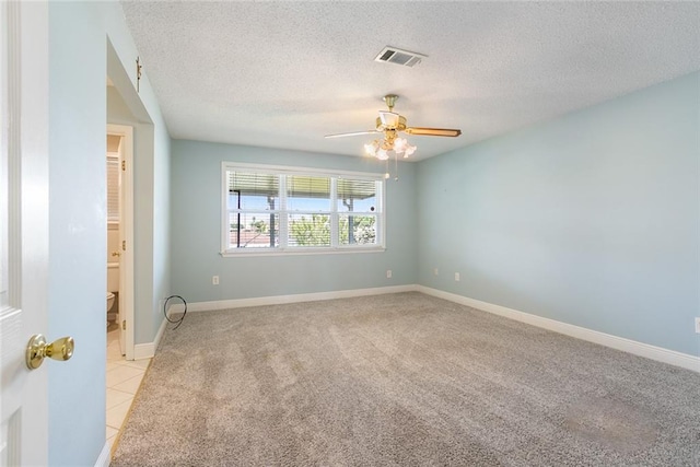 spare room featuring ceiling fan, light colored carpet, and a textured ceiling