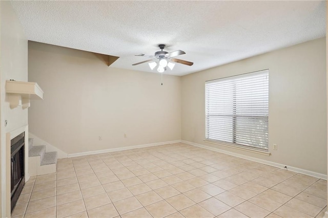 unfurnished living room featuring ceiling fan, light tile patterned floors, and a textured ceiling