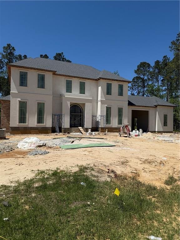 back of house featuring stucco siding and a shingled roof