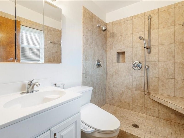 bathroom featuring tiled shower, vanity, and toilet