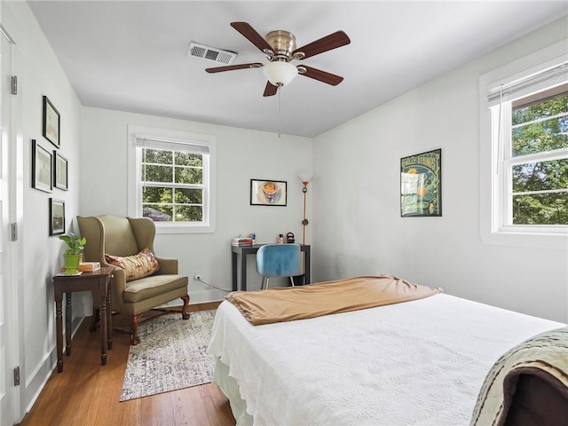 bedroom with multiple windows, hardwood / wood-style flooring, and ceiling fan