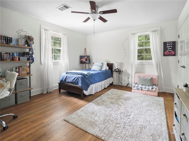 bedroom featuring ceiling fan, dark hardwood / wood-style flooring, and multiple windows