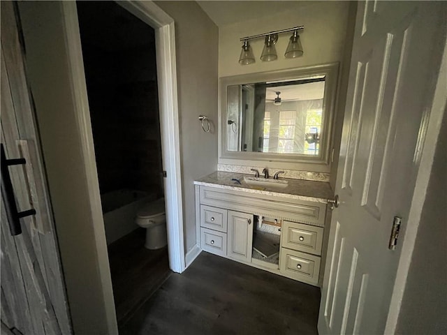 bathroom featuring wood-type flooring, vanity, toilet, and ceiling fan