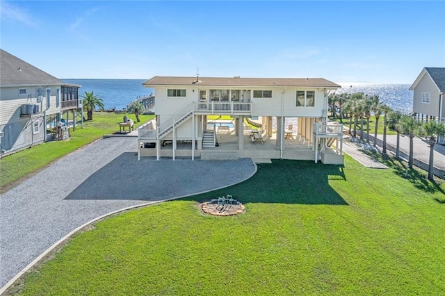 back of house with a lawn and a water view