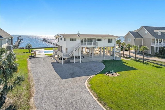 view of front of home featuring central AC unit, a water view, a balcony, and a front lawn