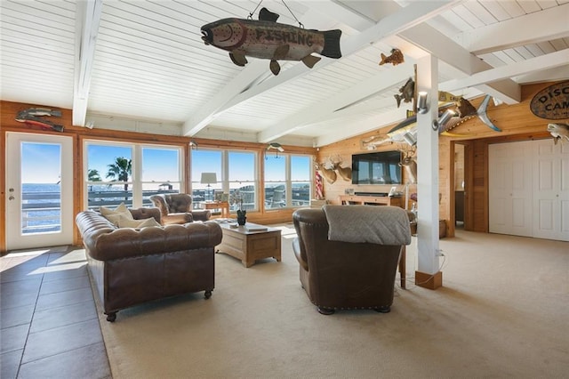 living room featuring lofted ceiling with beams, wood walls, and light colored carpet