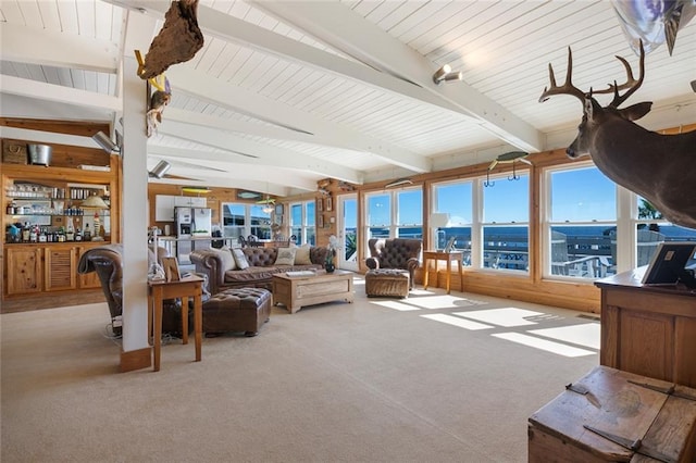 living room featuring beamed ceiling, light colored carpet, and indoor bar