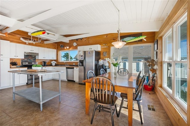 tiled dining room featuring vaulted ceiling with beams and sink