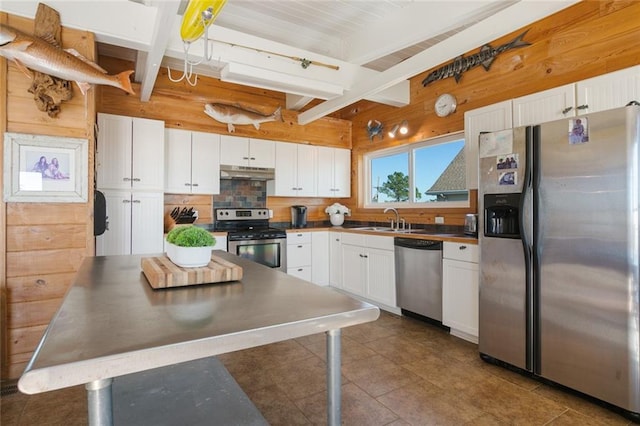 kitchen with backsplash, white cabinets, sink, appliances with stainless steel finishes, and beamed ceiling