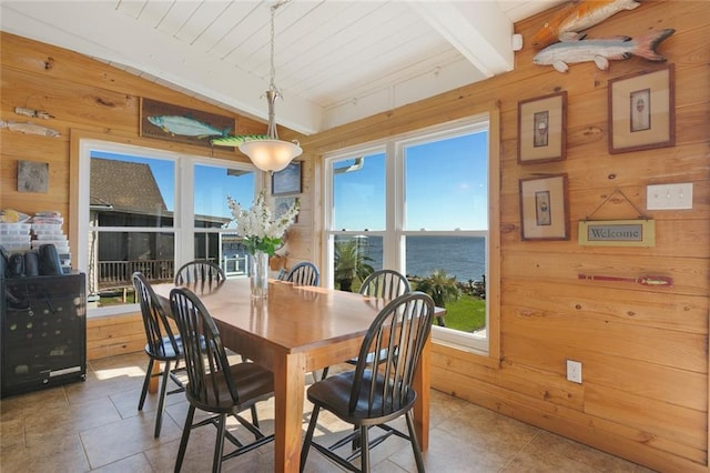 tiled dining space with wood walls, beamed ceiling, a water view, and wood ceiling