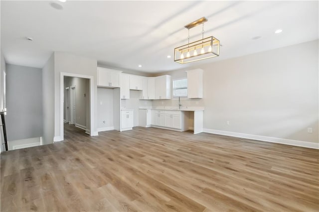 unfurnished living room featuring sink and light hardwood / wood-style flooring