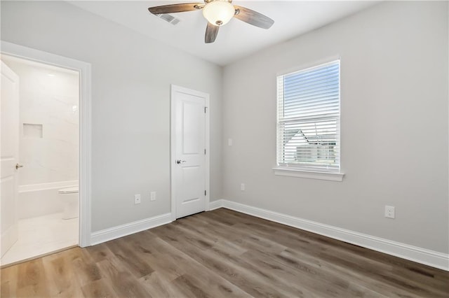 unfurnished bedroom featuring connected bathroom, ceiling fan, and hardwood / wood-style floors