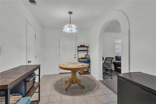 dining space featuring light tile patterned flooring and a textured ceiling