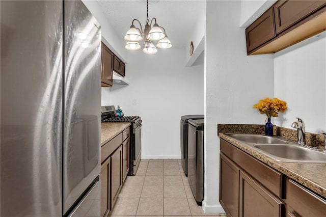 kitchen with washing machine and clothes dryer, sink, stainless steel appliances, a chandelier, and pendant lighting