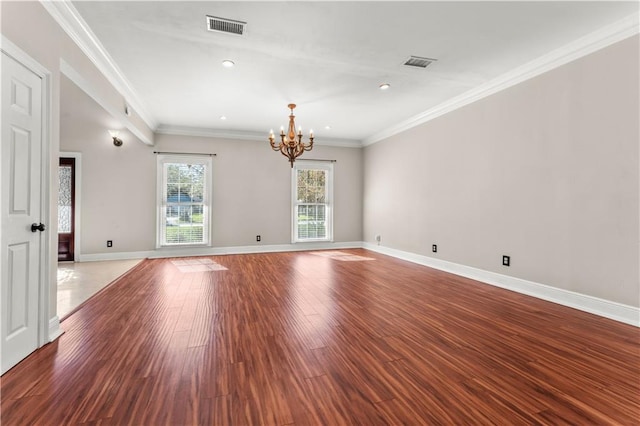 spare room with hardwood / wood-style flooring, crown molding, and an inviting chandelier