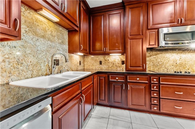 kitchen with sink, stainless steel appliances, tasteful backsplash, dark stone counters, and light tile patterned floors