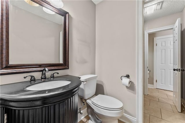 bathroom with tile patterned flooring, vanity, toilet, and a textured ceiling