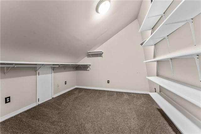 spacious closet with dark carpet and lofted ceiling