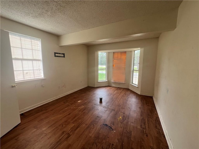 spare room with dark hardwood / wood-style flooring, plenty of natural light, and a textured ceiling