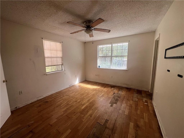 spare room with a textured ceiling, ceiling fan, and dark wood-type flooring