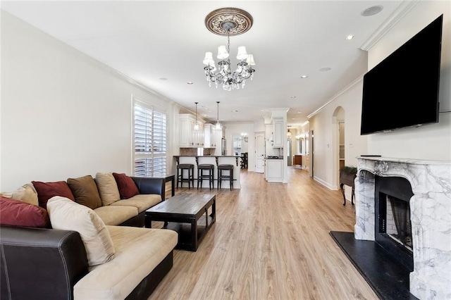 living room featuring light wood-type flooring, an inviting chandelier, and ornamental molding