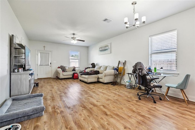 living room featuring ceiling fan with notable chandelier and light hardwood / wood-style flooring