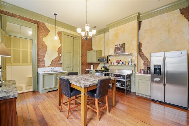 dining room featuring ornamental molding, a chandelier, brick wall, and light wood-type flooring