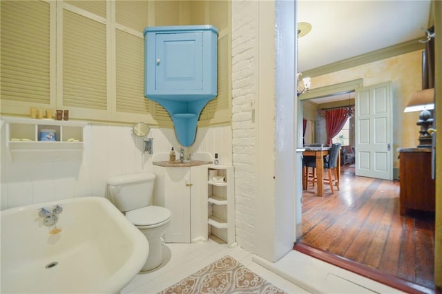 bathroom with hardwood / wood-style flooring, a washtub, and toilet