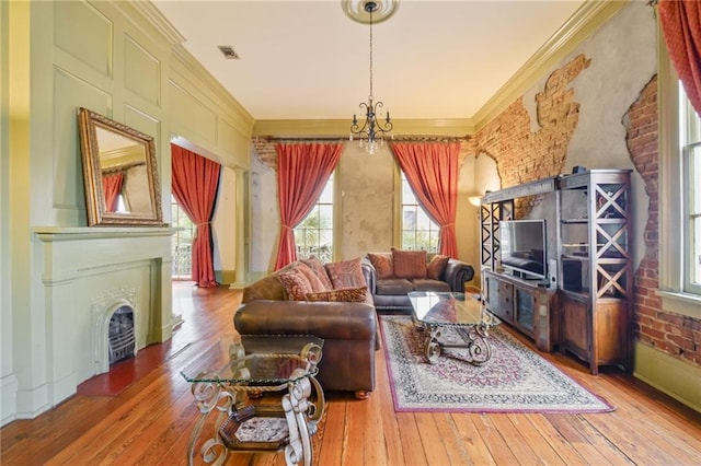 living room featuring an inviting chandelier, wood-type flooring, brick wall, and ornamental molding