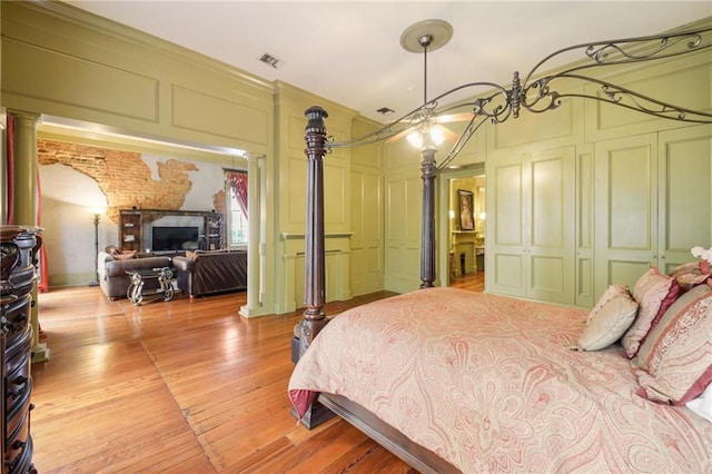 bedroom with light hardwood / wood-style flooring and ornate columns