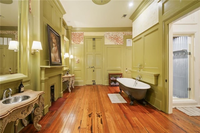 bathroom featuring a tub to relax in, crown molding, sink, and hardwood / wood-style floors