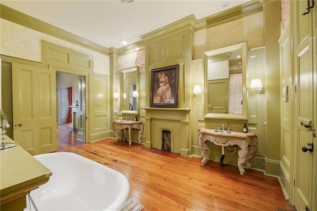 bathroom with hardwood / wood-style floors, crown molding, and a tub