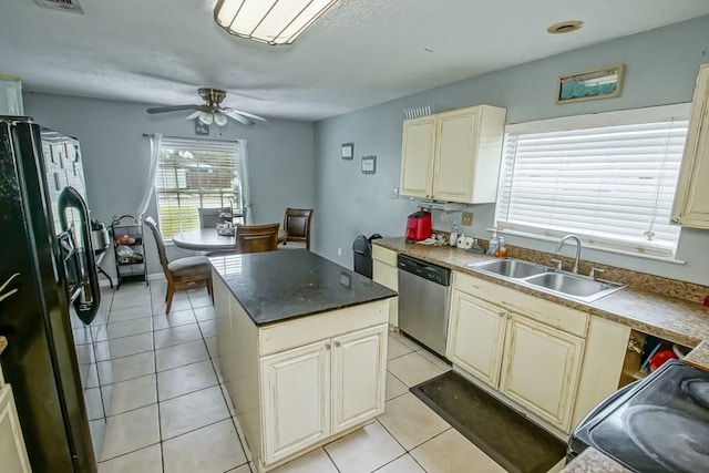 kitchen featuring dishwasher, cream cabinets, black fridge, sink, and a kitchen island