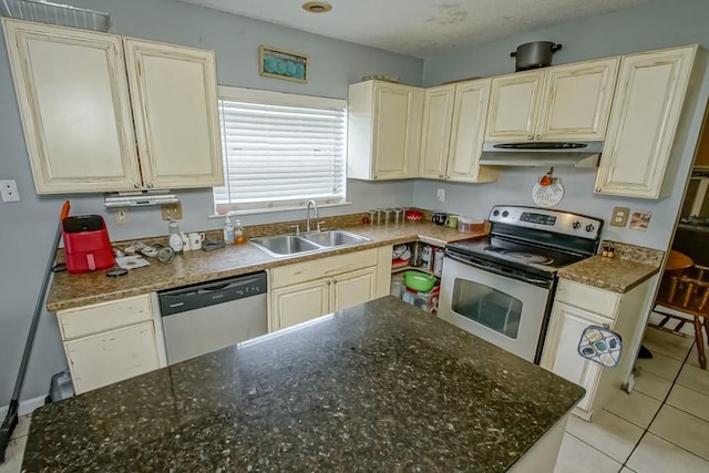 kitchen with dark stone countertops, sink, light tile patterned floors, and stainless steel appliances