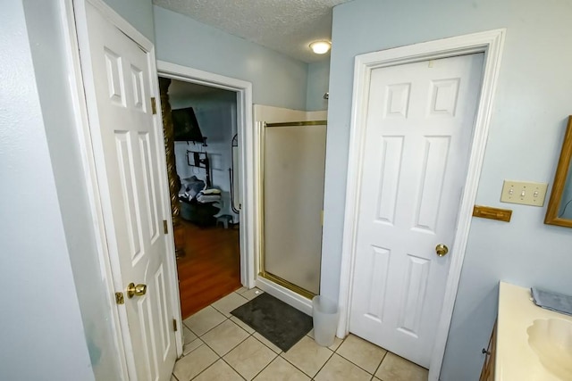 bathroom featuring a textured ceiling, tile patterned floors, and a shower with shower door