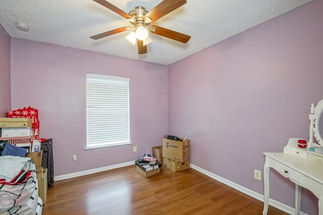 bedroom with ceiling fan, a textured ceiling, and hardwood / wood-style flooring