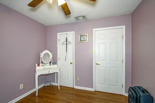 interior space featuring ceiling fan, wood-type flooring, and a textured ceiling