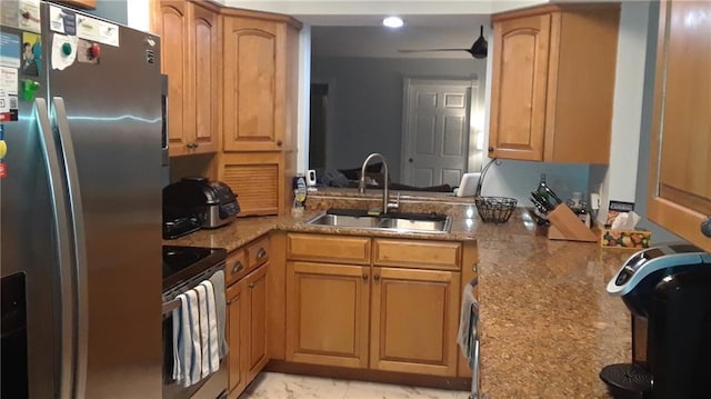 kitchen with appliances with stainless steel finishes, light stone counters, ceiling fan, and sink