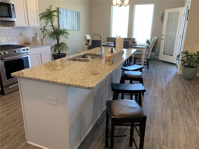 kitchen with white cabinetry, sink, a kitchen bar, and stainless steel appliances