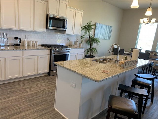 kitchen featuring white cabinetry, sink, a chandelier, decorative light fixtures, and appliances with stainless steel finishes