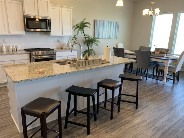 kitchen featuring appliances with stainless steel finishes, white cabinetry, pendant lighting, and sink