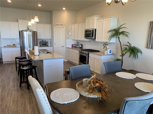 kitchen featuring tasteful backsplash, light stone counters, hanging light fixtures, and appliances with stainless steel finishes