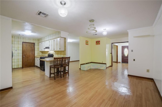 kitchen with white cabinetry, black gas stove, a chandelier, and light wood-type flooring