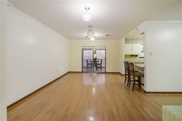 dining room with an inviting chandelier, ornamental molding, and light hardwood / wood-style flooring