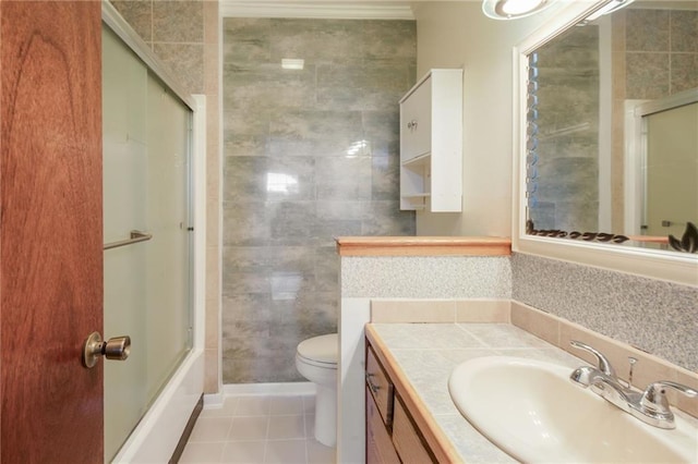 full bathroom featuring combined bath / shower with glass door, tile patterned floors, vanity, tile walls, and toilet