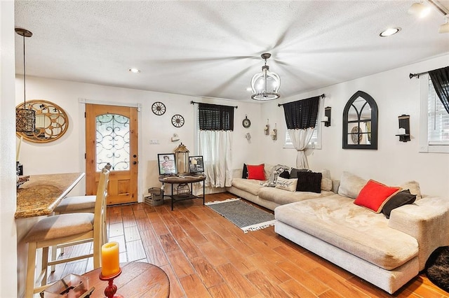 living room featuring hardwood / wood-style floors, a notable chandelier, and a textured ceiling