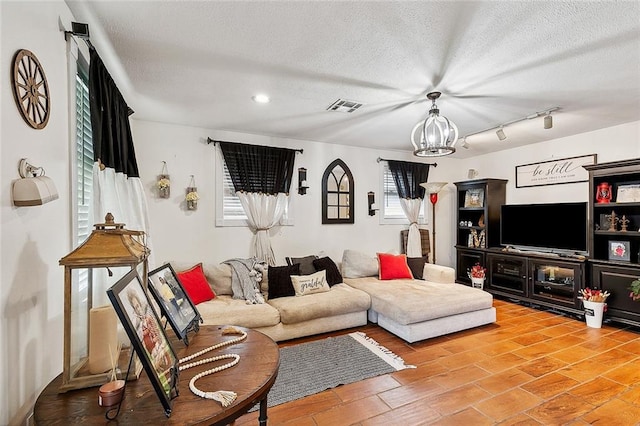 living room with hardwood / wood-style floors, a notable chandelier, a textured ceiling, and track lighting