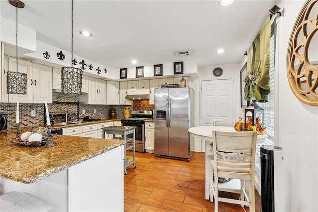 kitchen featuring backsplash, sink, appliances with stainless steel finishes, decorative light fixtures, and kitchen peninsula