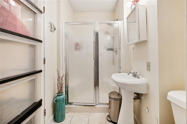 bathroom featuring tile patterned flooring, toilet, and a shower with door