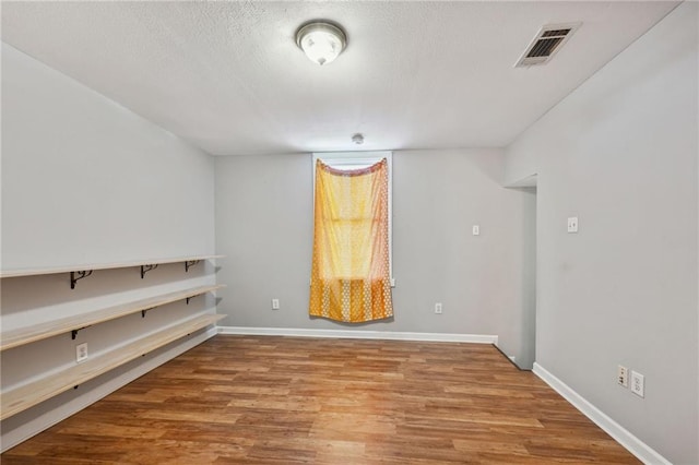 spare room with a textured ceiling and light hardwood / wood-style flooring